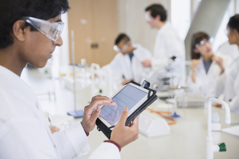 Ein männlicher Student benutzt ein digitales Tablet in einem wissenschaftlichen Labor, lizenzfreies Stockfoto