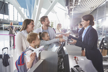 Customer service representative checking family tickets at airport check-in counter - CAIF10018
