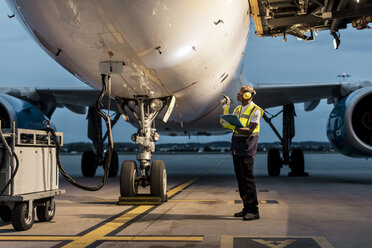 Airport ground crew worker checking airplane on tarmac - CAIF10028