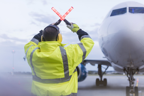 Air traffic controller guiding airplane with wand lights on tarmac stock photo