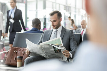 Geschäftsmann liest Zeitung im Abflugbereich des Flughafens - CAIF10046