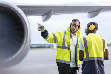 Mitarbeiter des Bodenpersonals der Flugsicherung unterhalten sich in der Nähe eines Flugzeugs auf dem Rollfeld eines Flughafens - CAIF10047