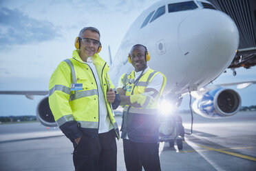 Porträt selbstbewusster Flugsicherungsmitarbeiter in der Nähe eines Flugzeugs auf dem Rollfeld eines Flughafens - CAIF10054