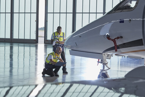 Bodenpersonal der Flugsicherung bei der Untersuchung eines Firmenjets in einem Flugzeughangar - CAIF10055
