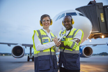 Porträt selbstbewusster Flugsicherungsmitarbeiter in der Nähe eines Flugzeugs auf dem Rollfeld eines Flughafens - CAIF10061