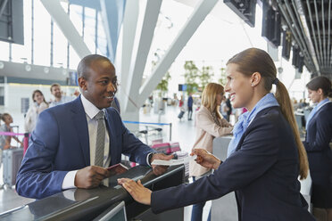 Kundendienstmitarbeiter, der einem Geschäftsmann am Flughafen-Check-in-Schalter hilft - CAIF10065