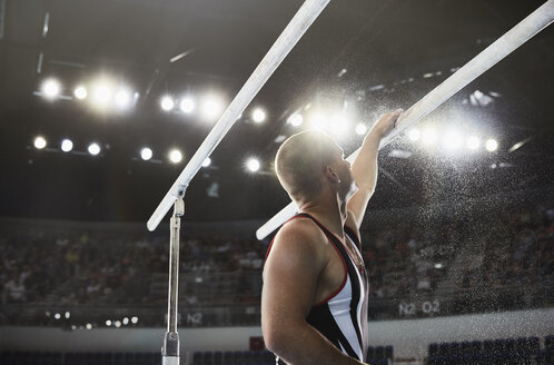 Male gymnast applying chalk powder to parallel bars - CAIF10101