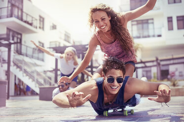 Playful young couple riding skateboard - CAIF10140