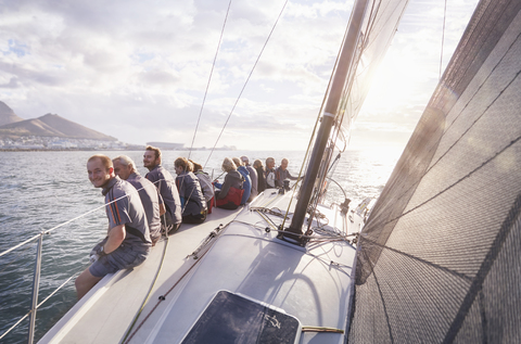 Freunde im Ruhestand sitzen auf einem Segelboot auf dem sonnigen Meer, lizenzfreies Stockfoto