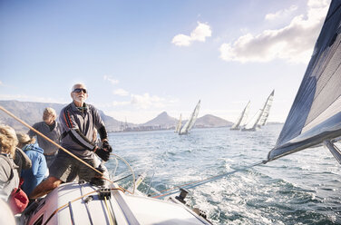 Mann beim Einstellen der Takelage eines Segelboots auf dem sonnigen Meer - CAIF10166