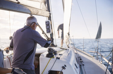 Man adjusting sailing equipment on sailboat - CAIF10175
