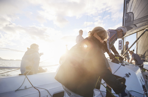 Freunde stellen die Segelausrüstung auf einem sonnigen Segelboot ein, lizenzfreies Stockfoto
