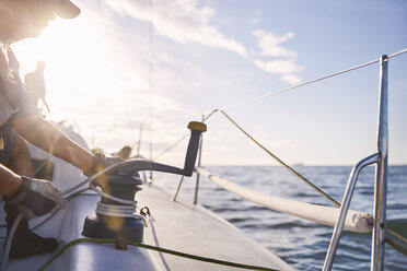 Man adjusting sailing winch on sailboat - CAIF10179