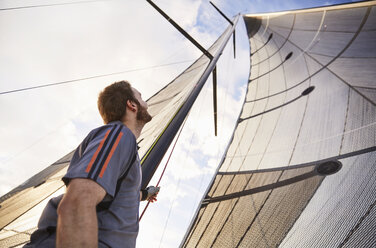 Man sailing looking up at sail - CAIF10185