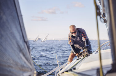 Retired man sailing sailboat - CAIF10190