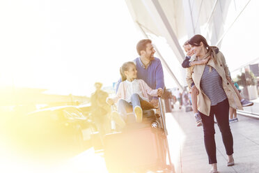 Familie zu Fuß mit Gepäckwagen vor dem Flughafen - CAIF10199