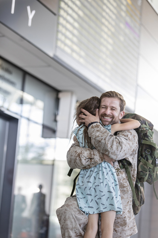 Tochter begrüßt und umarmt Soldatenvater am Flughafen, lizenzfreies Stockfoto