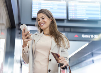 Geschäftsfrau mit Reisepass benutzt Mobiltelefon im Flughafen - CAIF10210