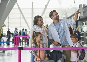 Familie mit Koffern, die in der Flughafenhalle zeigen - CAIF10214