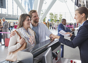 Customer service representative helping couple at airport check-in counter - CAIF10217