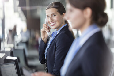 Porträt lächelnd Kundenbetreuer sprechen am Telefon am Flughafen Check-in Schalter - CAIF10219