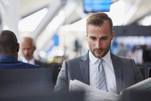 Geschäftsmann liest Zeitung im Abflugbereich des Flughafens - CAIF10227