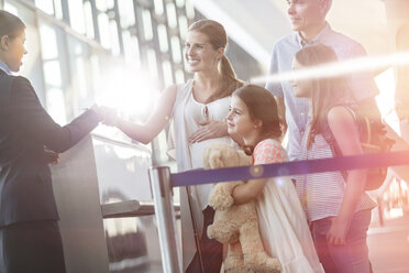 Flugbegleiter bei der Kontrolle der Tickets einer Familie im Flughafen - CAIF10231