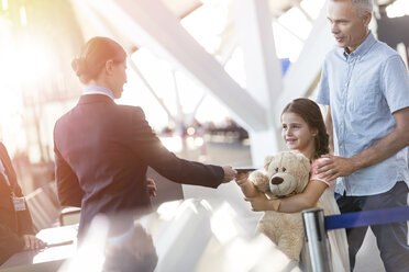 Flugbegleiter kontrolliert das Ticket eines Mädchens mit Teddybär im Flughafen - CAIF10244