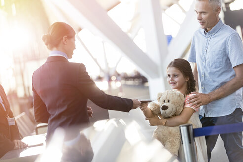 Flight attendant checking ticket of girl with teddy bear in airport - CAIF10244