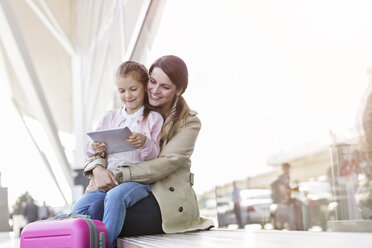 Mutter und Tochter benutzen digitales Tablet vor dem Flughafen - CAIF10246