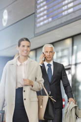 Geschäftsleute gehen und sprechen mit dem Handy in der Flughafenhalle - CAIF10247