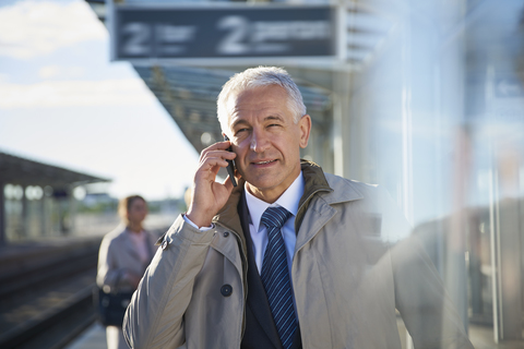 Geschäftsmann, der außerhalb des Flughafens mit einem Handy telefoniert, lizenzfreies Stockfoto