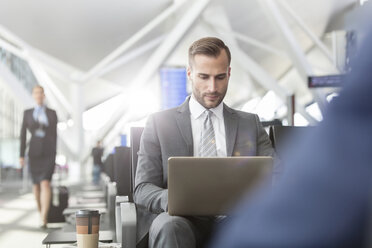 Geschäftsmann arbeitet mit Laptop im Abflugbereich des Flughafens - CAIF10256