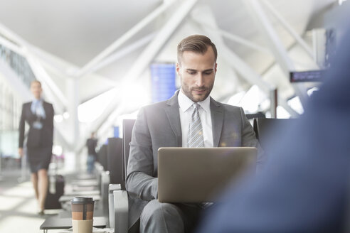 Geschäftsmann arbeitet mit Laptop im Abflugbereich des Flughafens - CAIF10256