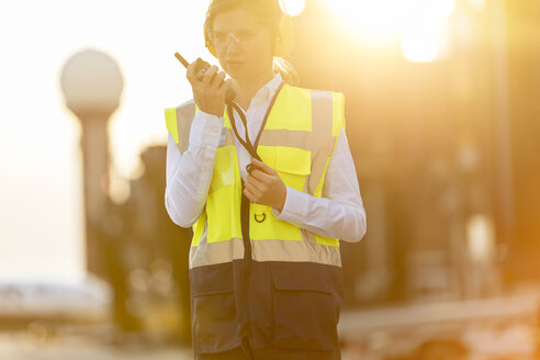 Fluglotse mit Walkie-Talkie auf dem Rollfeld eines Flughafens - CAIF10262