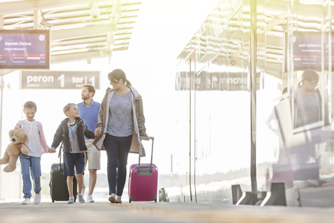 Familie geht mit Koffern in der Bahnhofshalle, lizenzfreies Stockfoto
