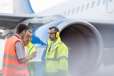 Air traffic control ground crew with clipboard next to airplane on tarmac - CAIF10267