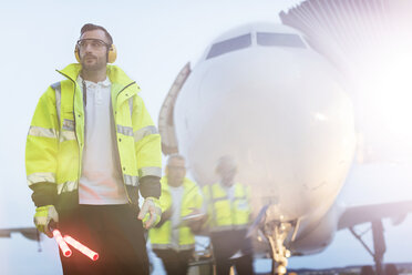 Air traffic controller standing in front of airplane on airport tarmac - CAIF10268