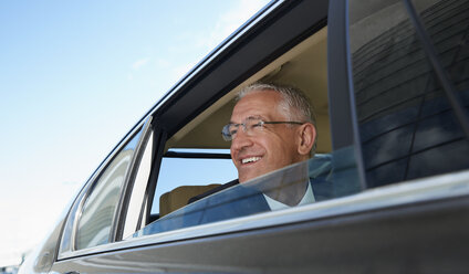 Lächelnder Geschäftsmann, der aus dem Fenster eines Stadtautos schaut - CAIF10299