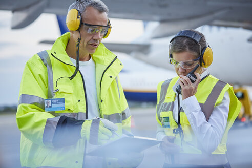 Bodenpersonal der Flugsicherung mit Klemmbrett im Gespräch auf dem Rollfeld des Flughafens - CAIF10300
