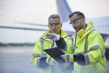 Bodenpersonal der Flugsicherung mit Klemmbrett im Gespräch auf dem Rollfeld des Flughafens - CAIF10304