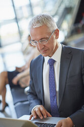 Geschäftsmann arbeitet mit Laptop im Flughafen - CAIF10317