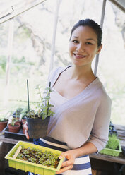 Porträt lächelnde Frau bei der Gartenarbeit im Gewächshaus - CAIF10343