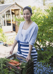 Porträt lächelnde Frau erntet Karotten im Garten - CAIF10345