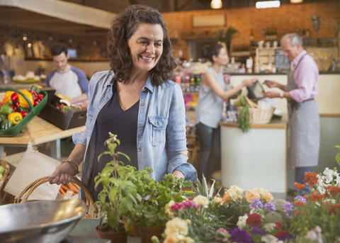 Lächelnde Frau beim Einkaufen von Blumen auf dem Markt, lizenzfreies Stockfoto