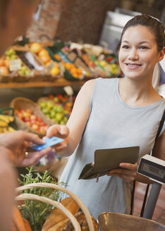 Frau zahlt mit Kreditkarte an der Kasse eines Lebensmittelgeschäfts - CAIF10350