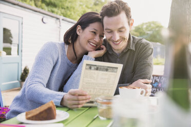 Smiling couple looking at menu at outdoor cafe - CAIF10357