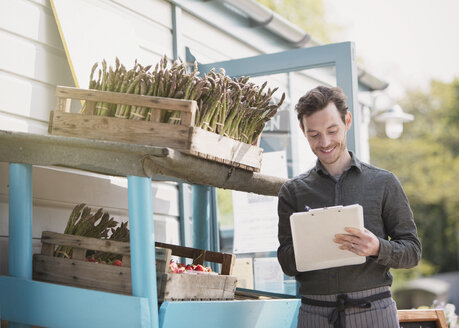 Farmerís market worker with clipboard checking inventory next to asparagus - CAIF10378