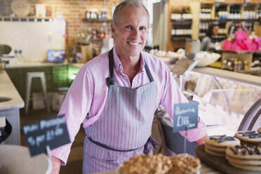 Portrait smiling worker behind desserts in market - CAIF10398