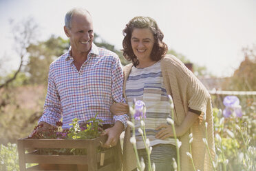 Smiling couple shopping for flowers in sunny plant nursery garden - CAIF10402